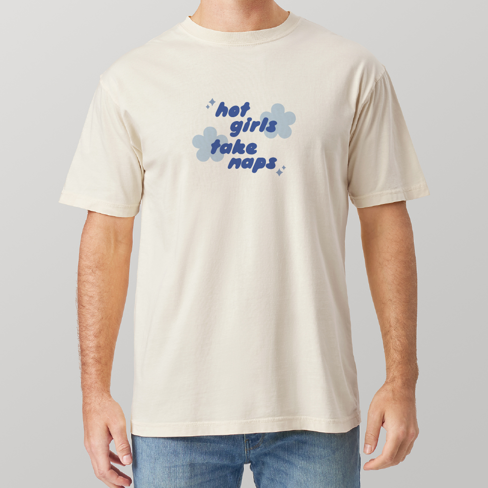 Man wearing a beige t-shirt with blue text spelling hot girls take naps and other graphics on a plain background