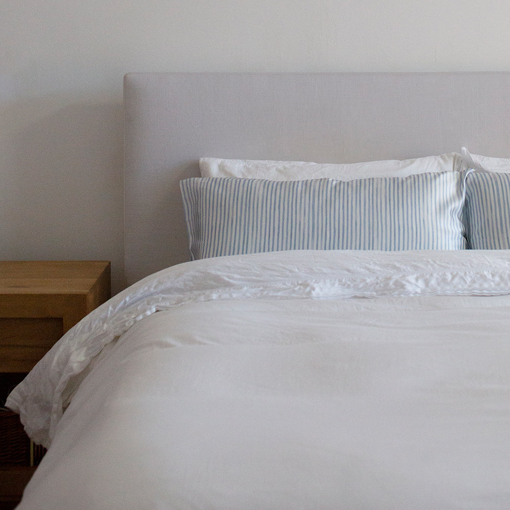 Queen size silk pillowcase with blue stripe print on a bed